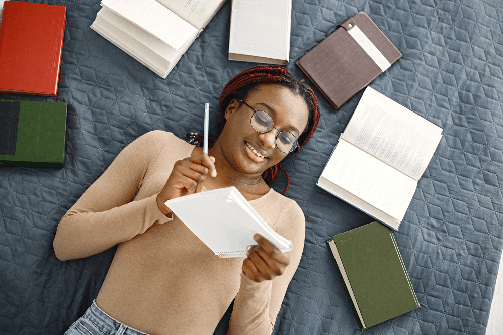 young-teenage-girl-lying-on-her-bed-studying-in-li-2022-09-08-17-39-03-utc